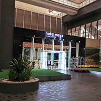 The exterior of Hotel Maya in Kuala Lumpur, featuring a modern facade, a well-lit entrance, and a landscaped area with a small garden and a water feature.
