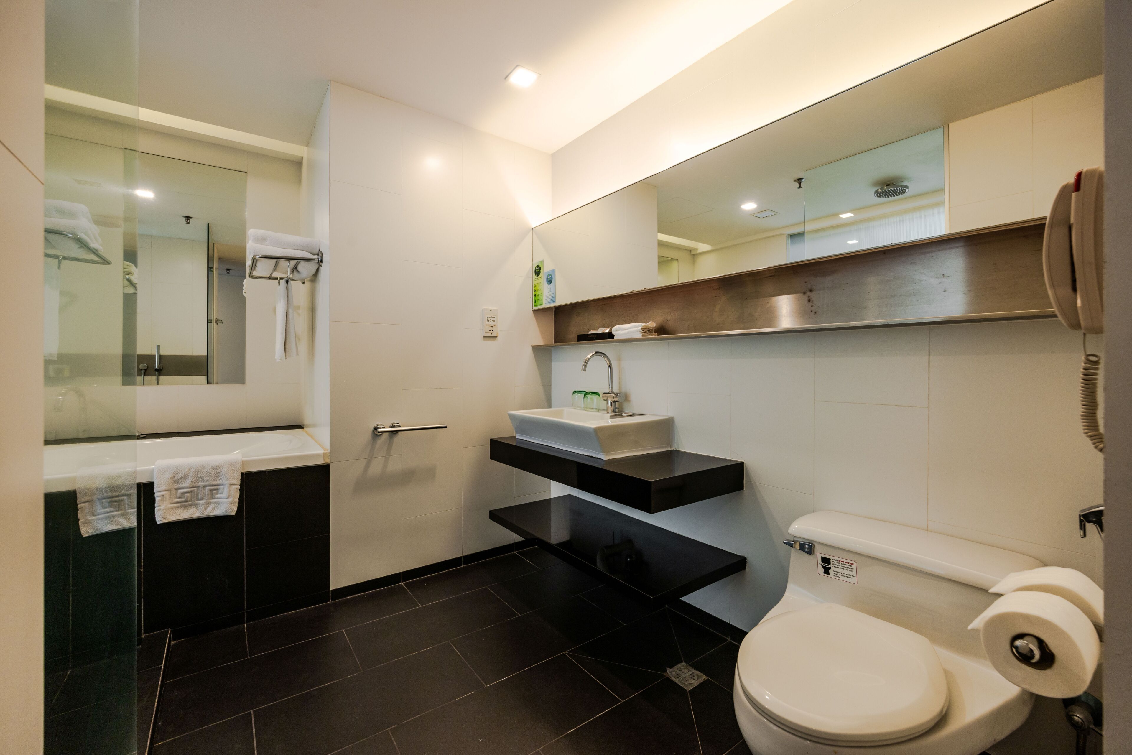A modern bathroom with a bathtub, a sink, a toilet, and a mirror.
