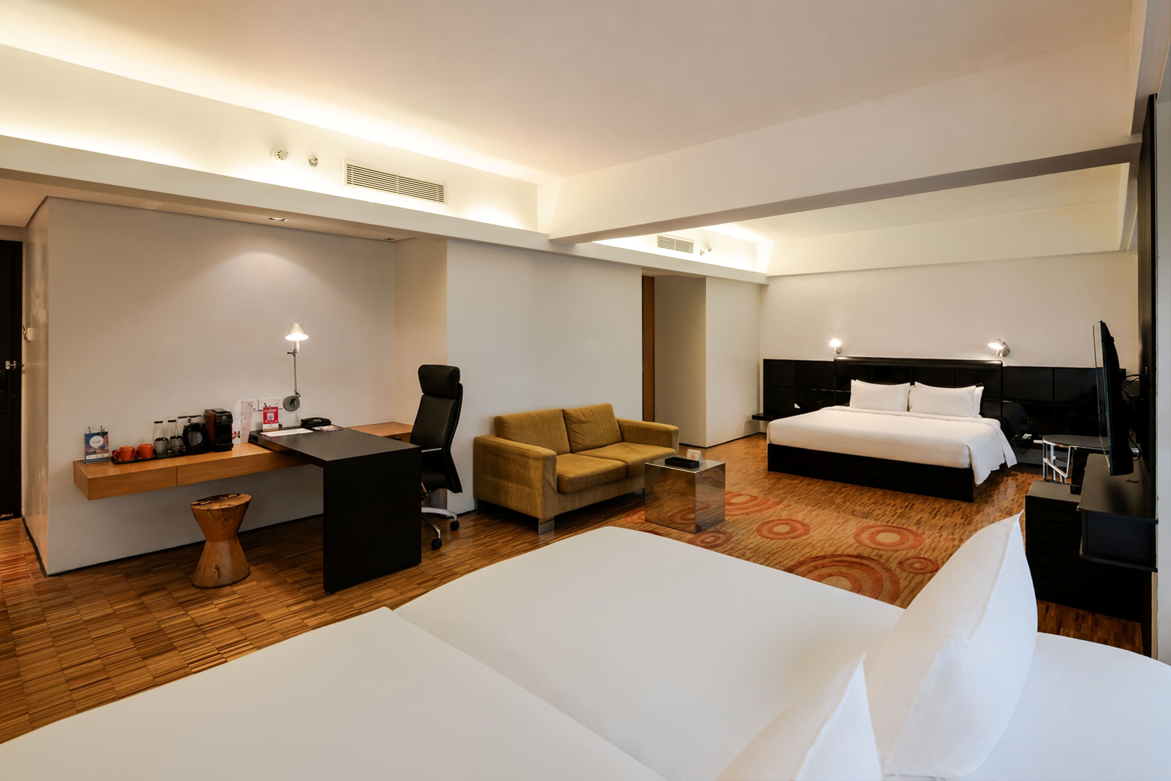 Habitació d'hotel amb llit, escriptori, cadira, sofà i televisió.