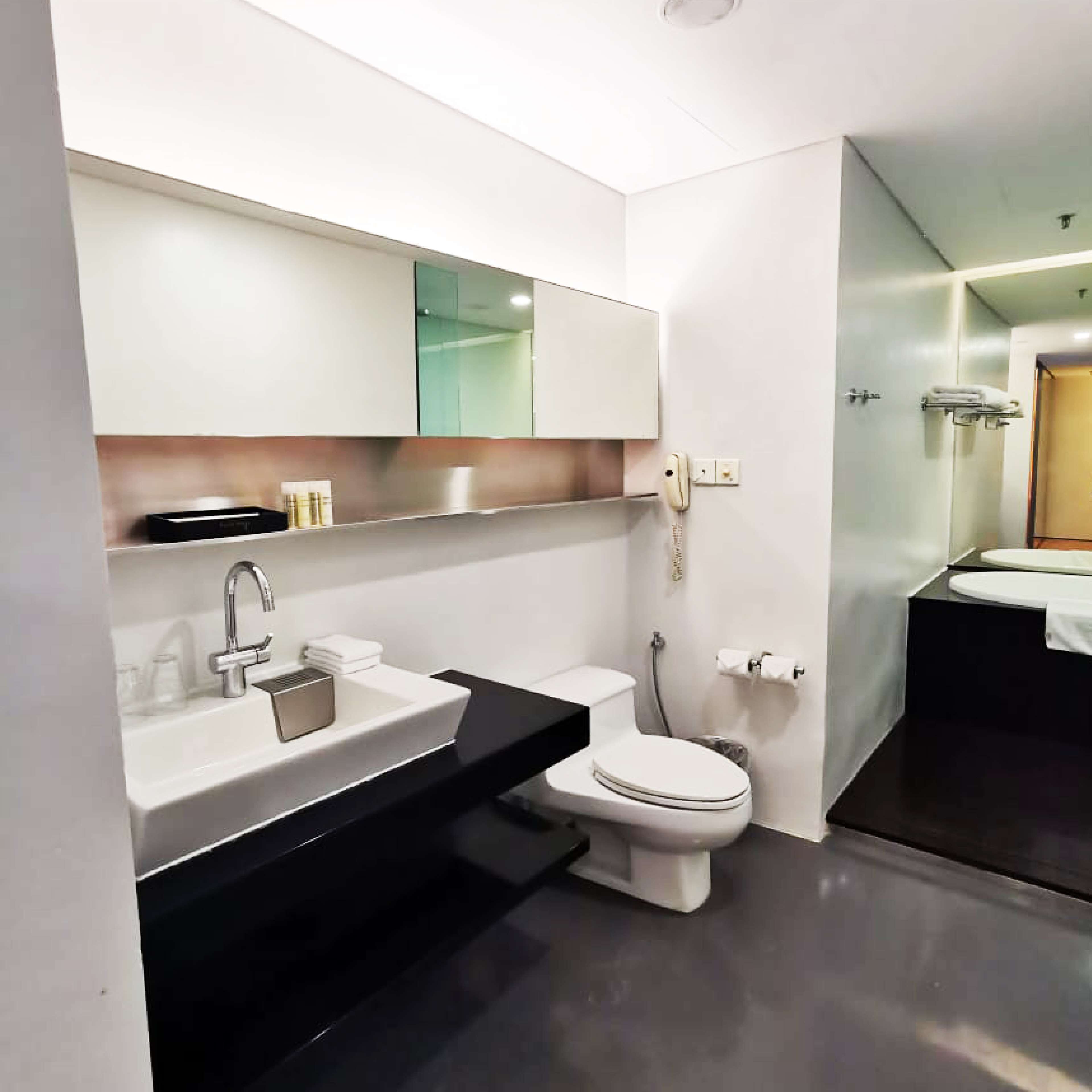 Un bany modern amb taulell negre, un lavabo blanc, un vàter i un mirall sobre el lavabo.