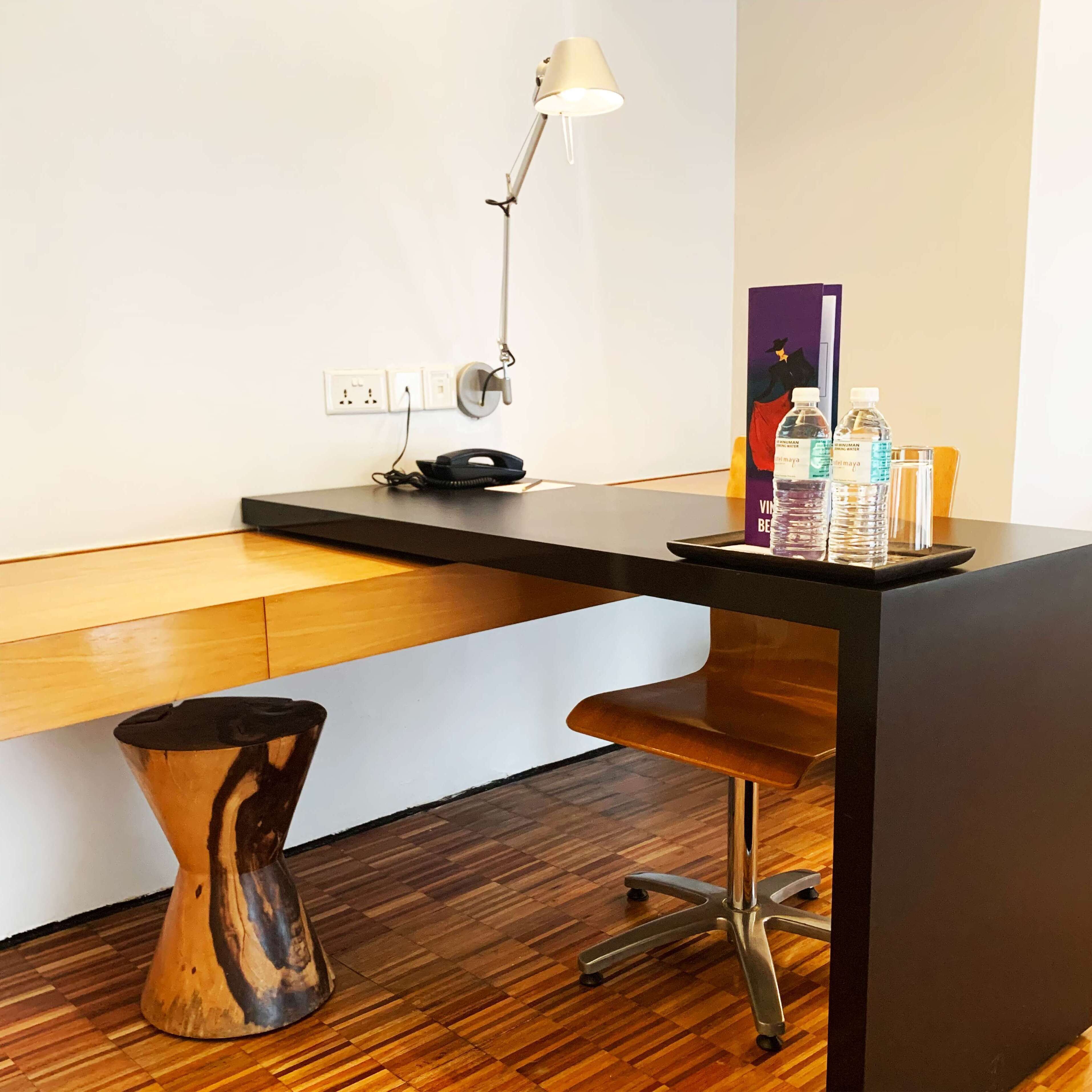 A modern office desk with a lamp, phone, and water bottles.