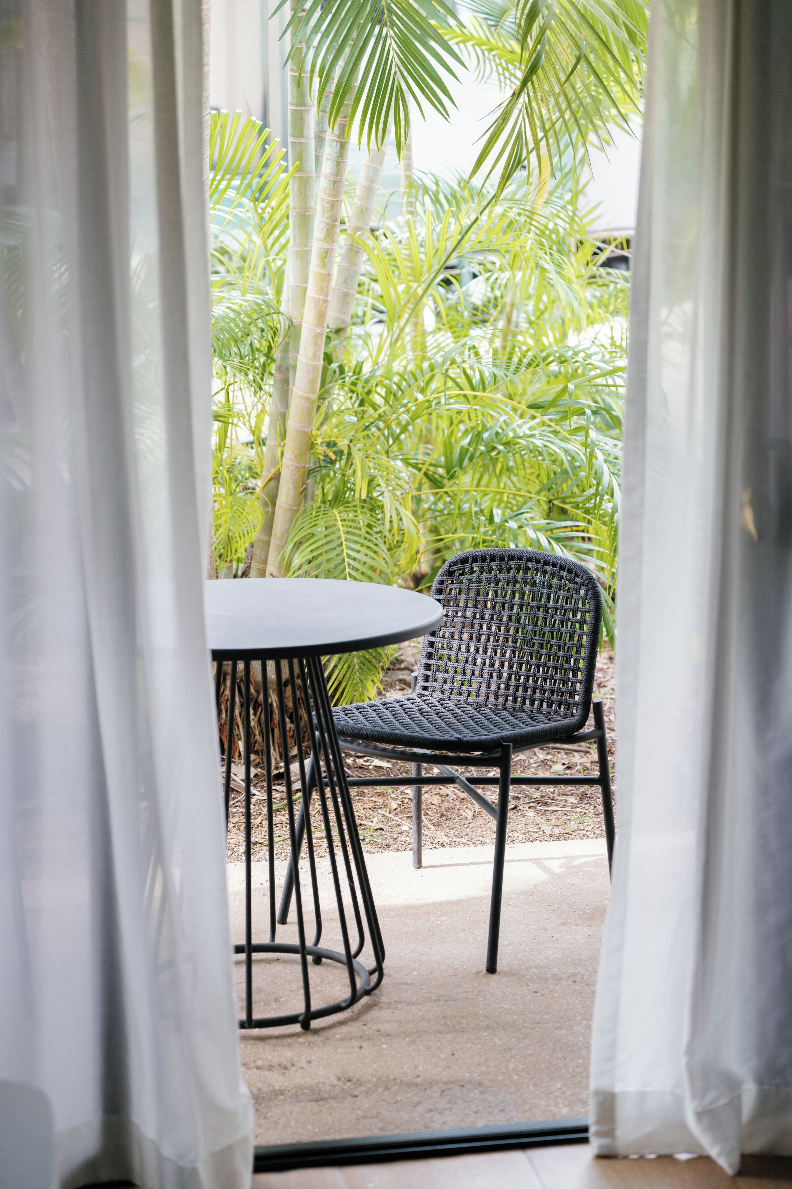 A room with a view of a garden, a table, and a chair.