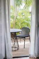 A room with a view of a garden, a table, and a chair.