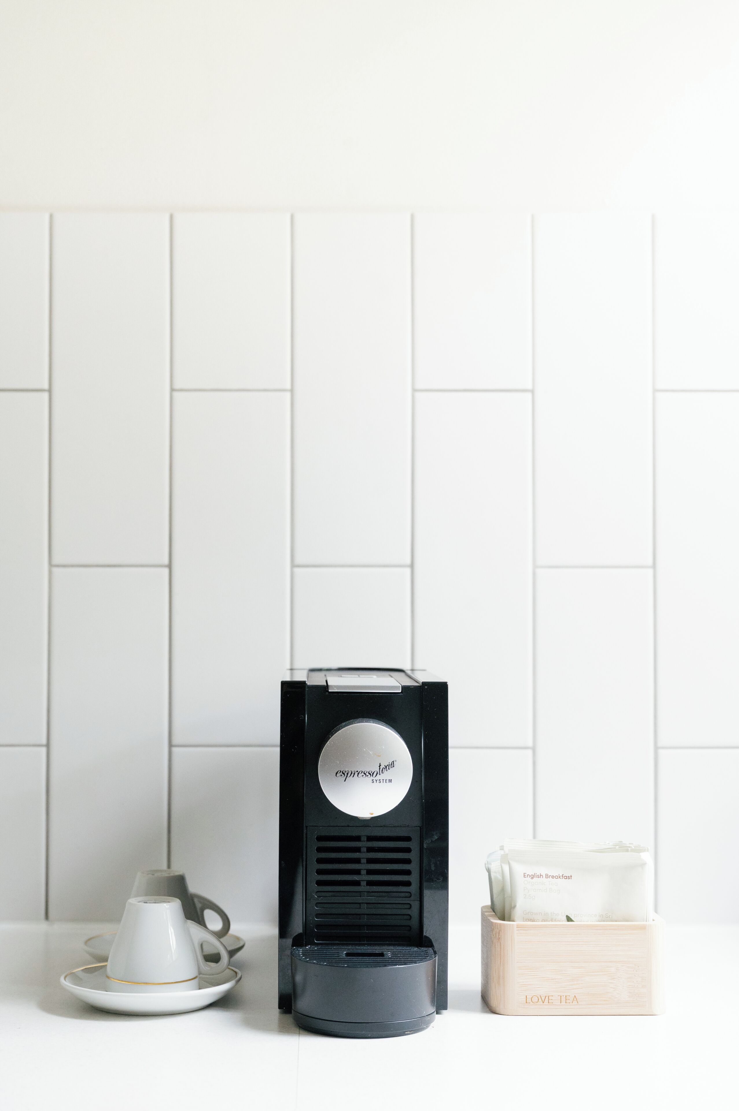 A coffee maker, a cup, and a box labeled 'LOVE TEA' on a white surface.