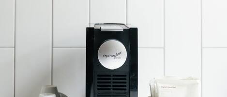 A coffee machine, a teapot, and a box of tea on a white countertop.