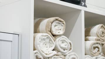 A white shelf with black kettlebells and neatly rolled towels.