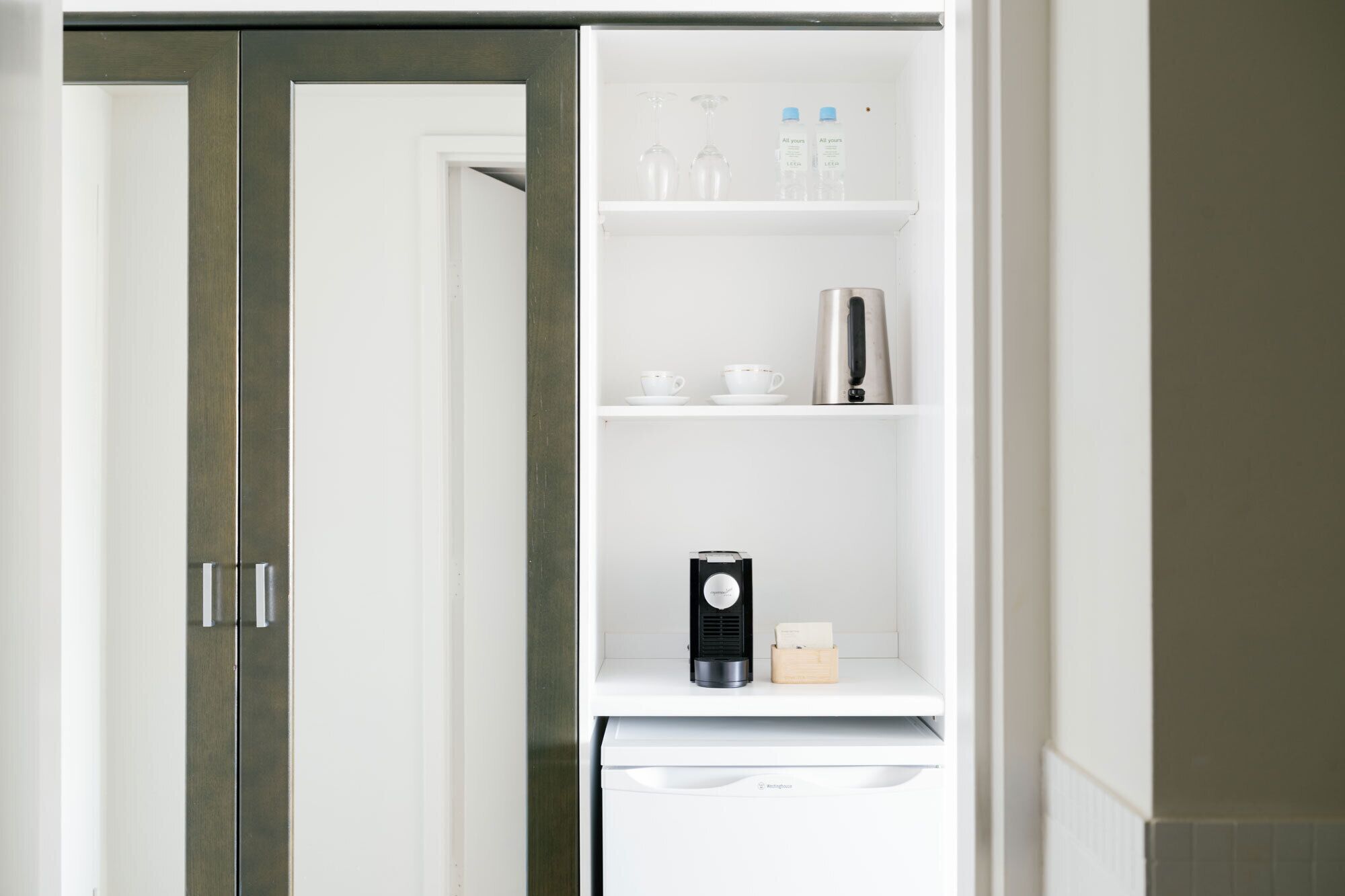 A white refrigerator with a coffee maker and a box of tissues on the door shelf.
