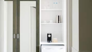 A white refrigerator with a coffee maker and a box of tissues on the door shelf.