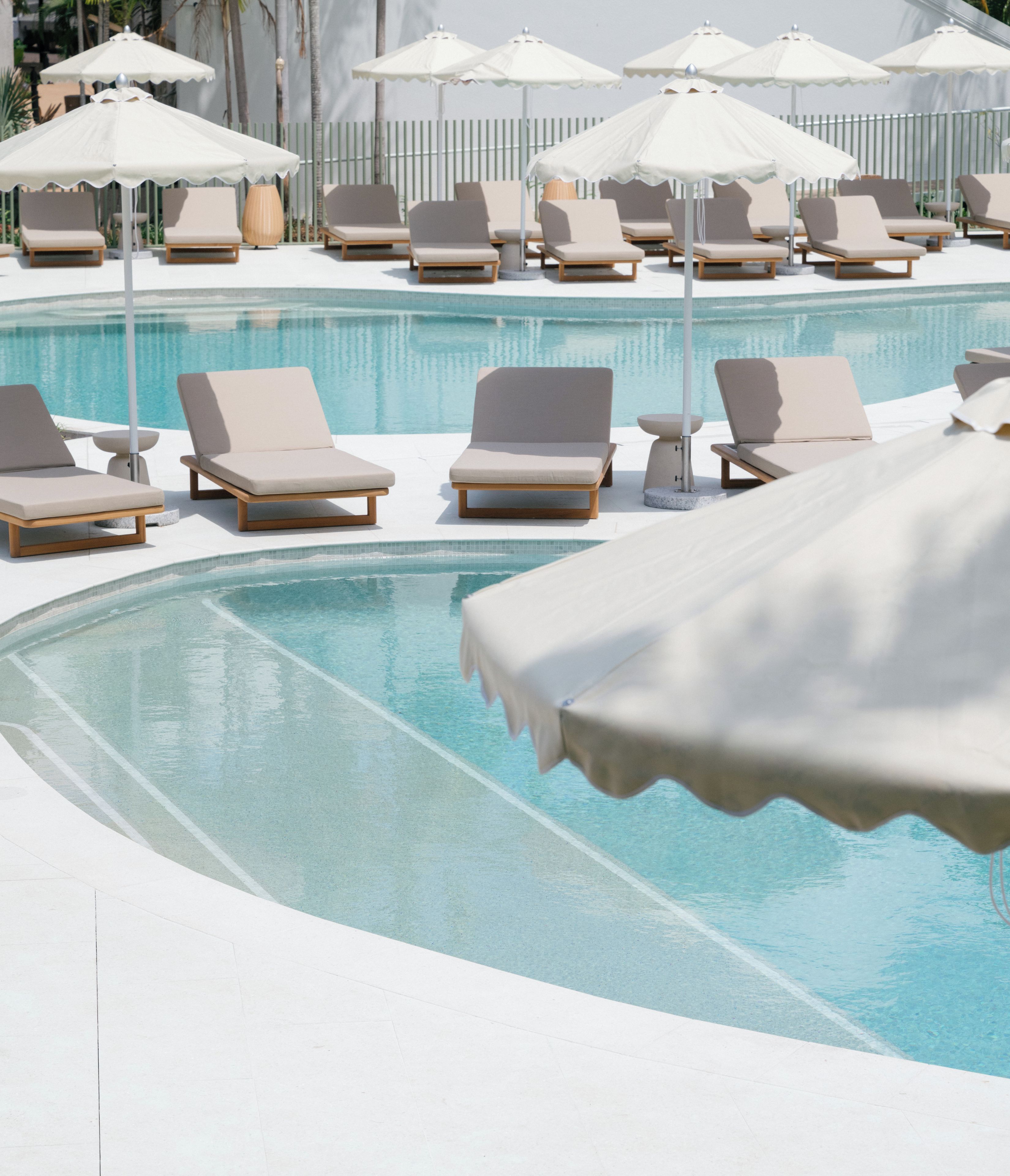 Ein Poolbereich mit Liegestühlen und Sonnenschirmen.