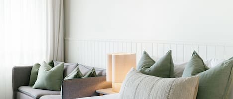 Una habitación de hotel con cama, una silla, una lámpara y una ventana con cortinas.