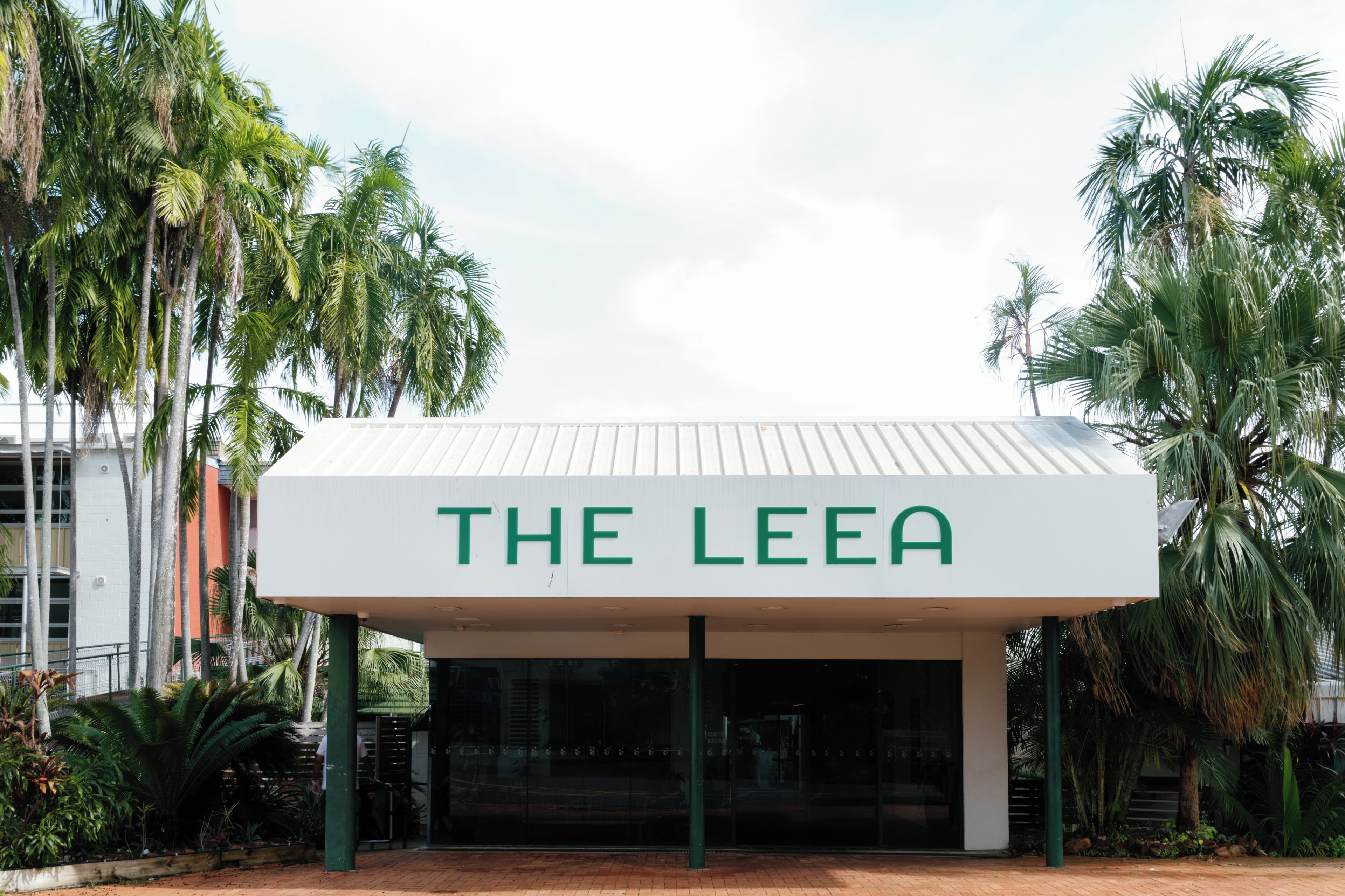 A building with a sign reading 'THE LEEA' and surrounded by palm trees.