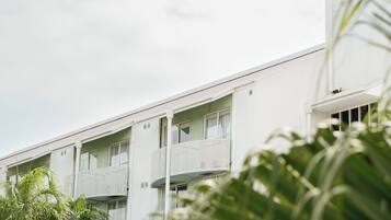 A multi-story building with balconies, surrounded by palm trees.