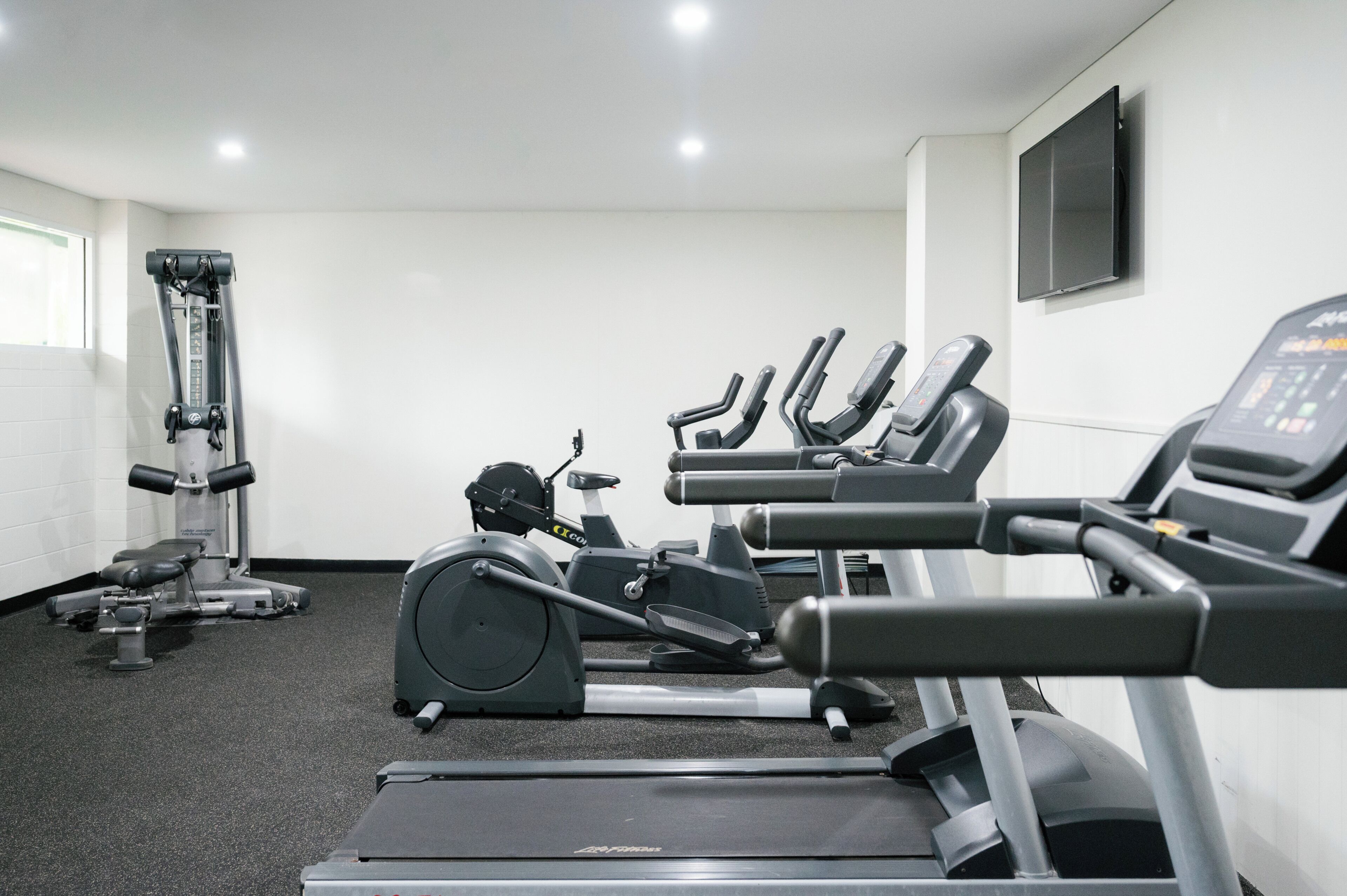 A gym with treadmills, stationary bikes, and a weight machine.