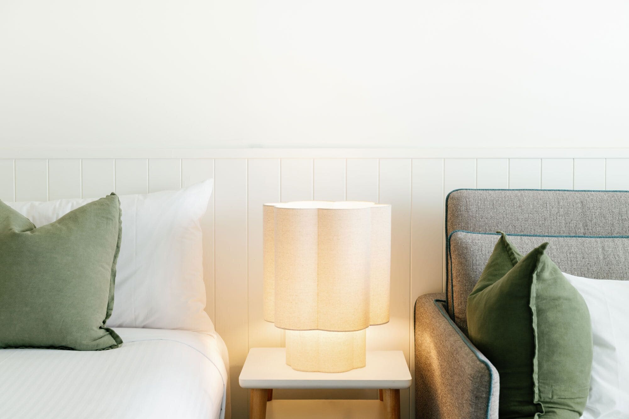 A neatly made bed with pillows, a bedside lamp, and a headboard.
