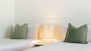 A hotel room with two beds, a nightstand, and a lamp.