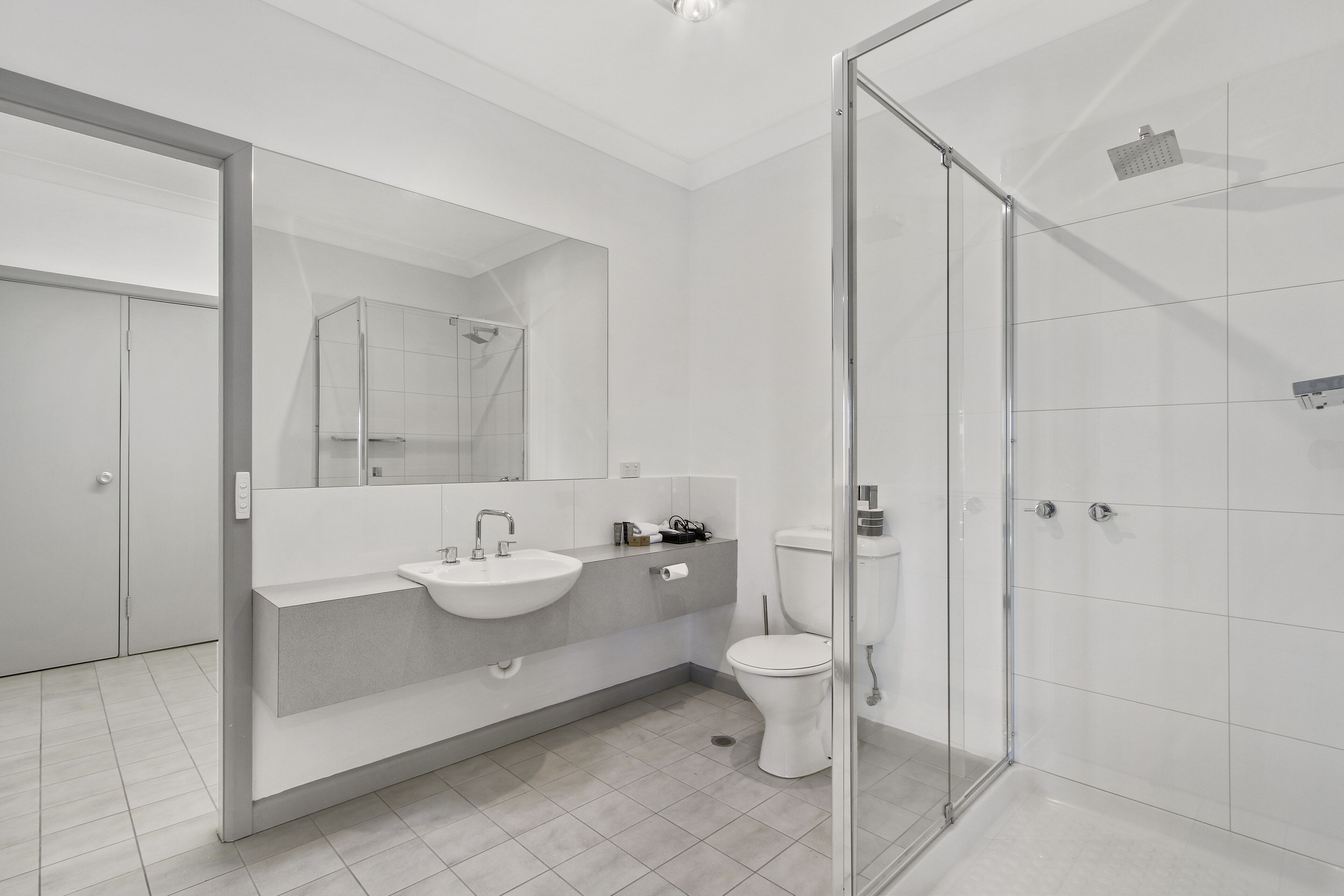 A modern bathroom with a glass-enclosed shower, a sink, and a toilet.