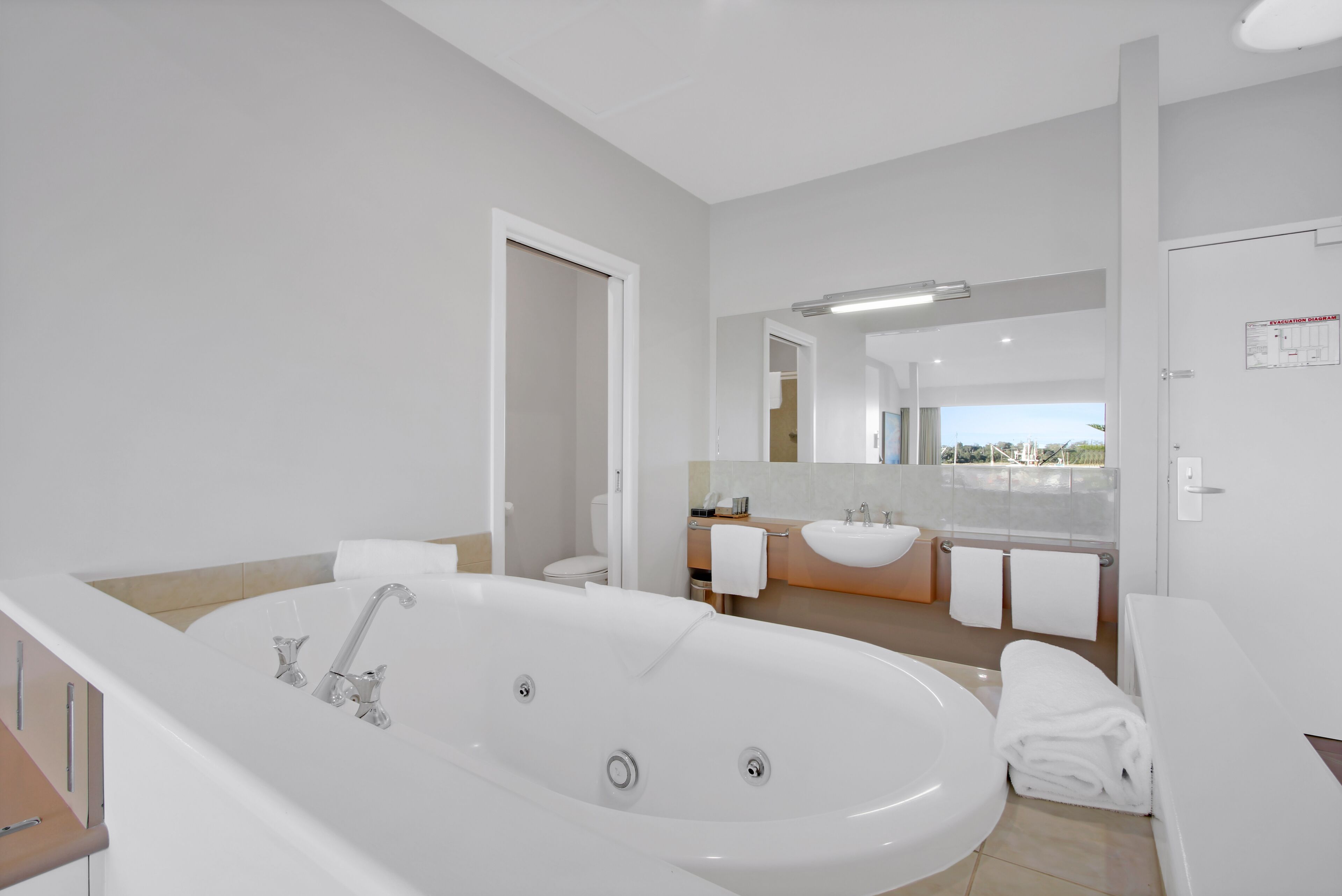 A modern bathroom with a large bathtub, a separate shower area, and a vanity with a sink and mirror.