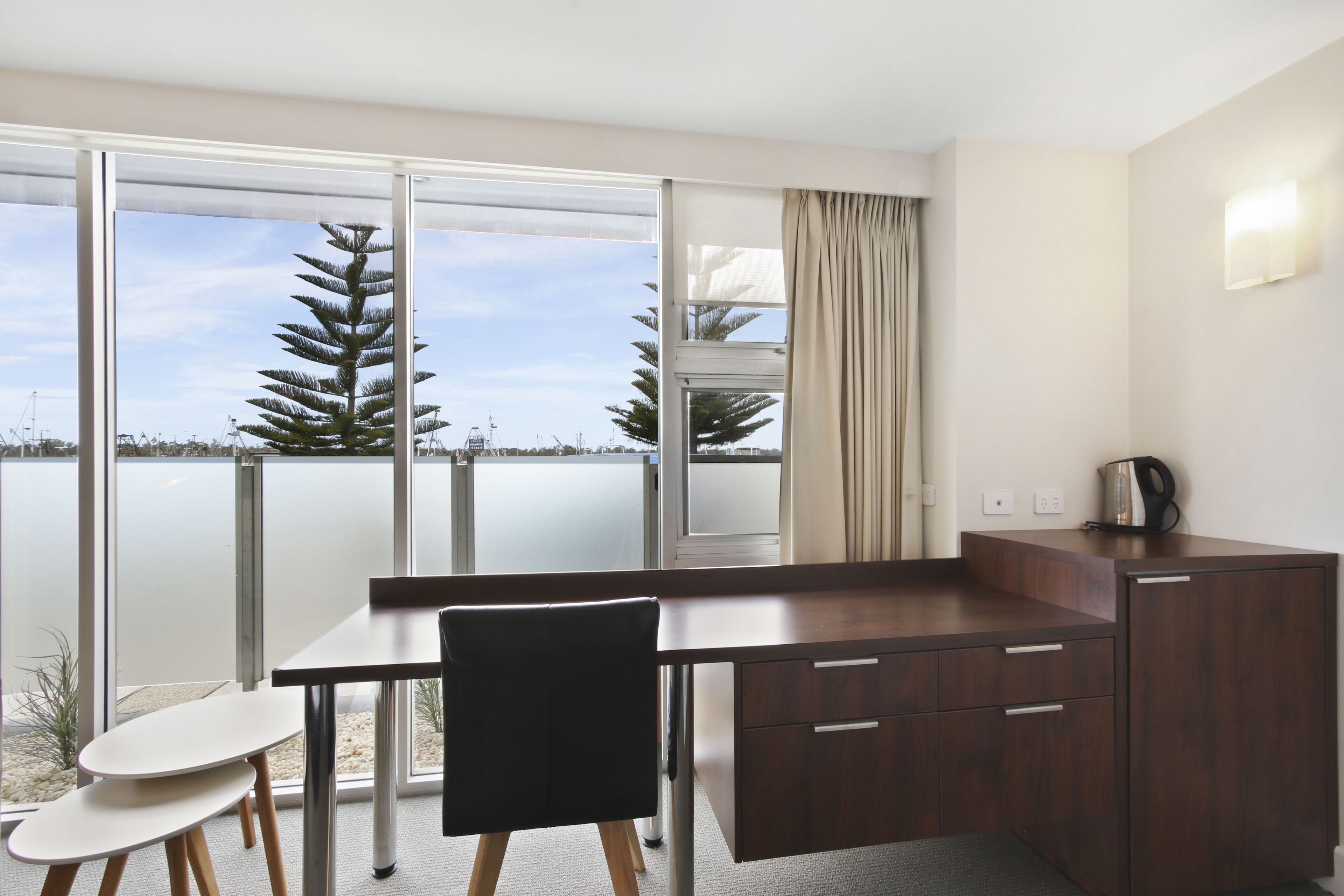 Una habitación moderna con un gran ventanal, un escritorio, una silla y un armario.