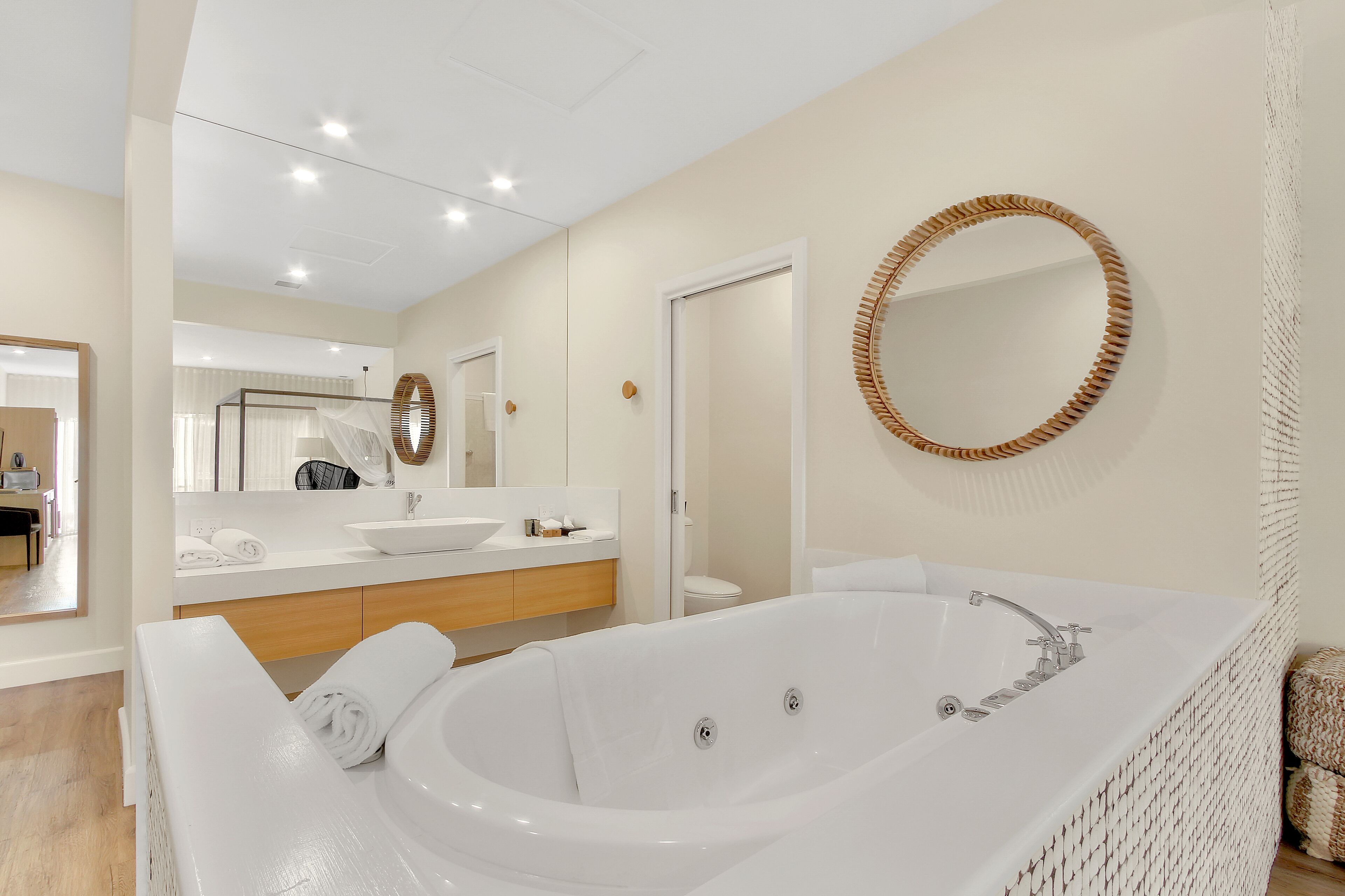 Un bagno moderno con una grande vasca, un mobile lavabo e uno specchio.
