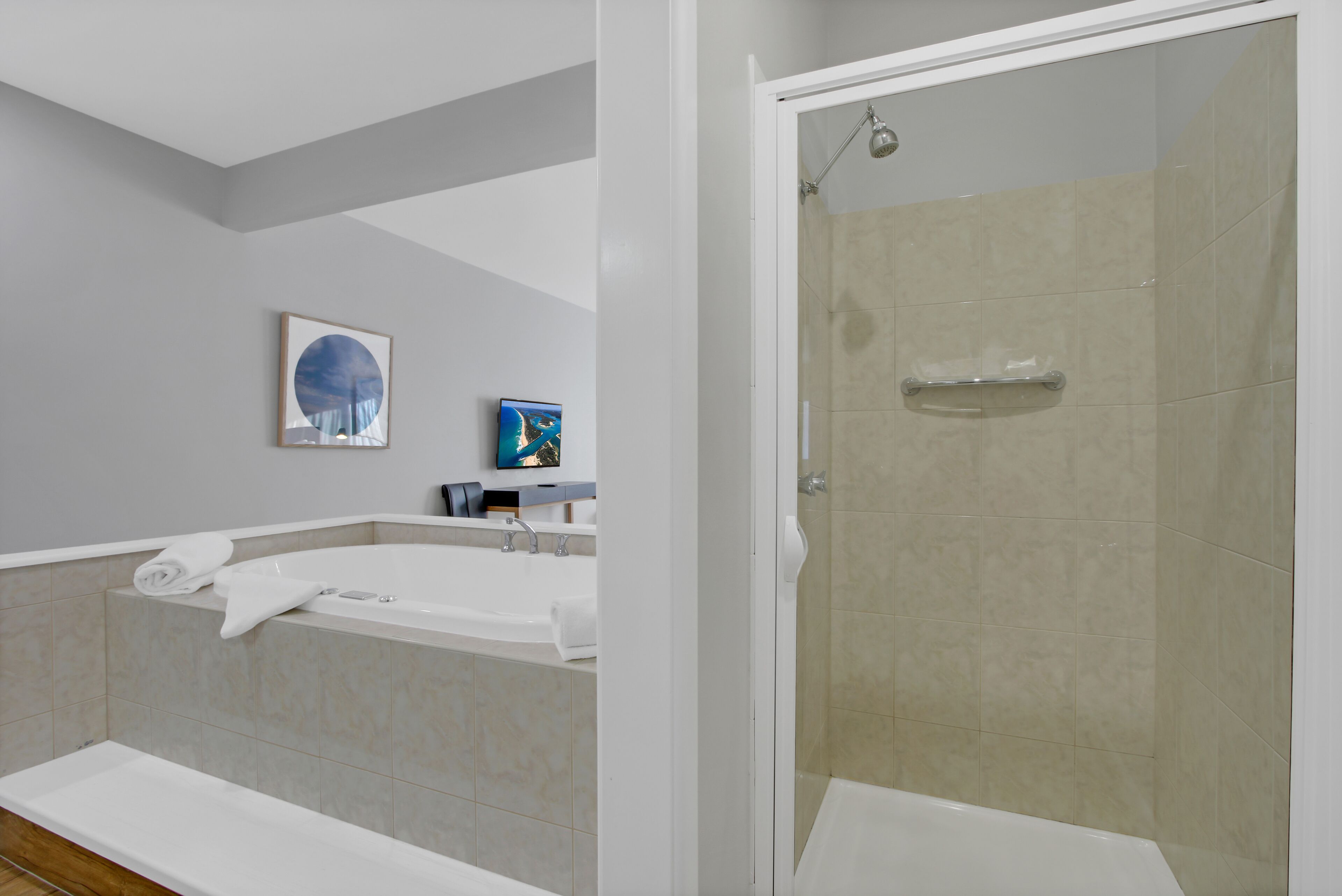 A modern bathroom with a bathtub, shower, and a glass-enclosed shower stall.