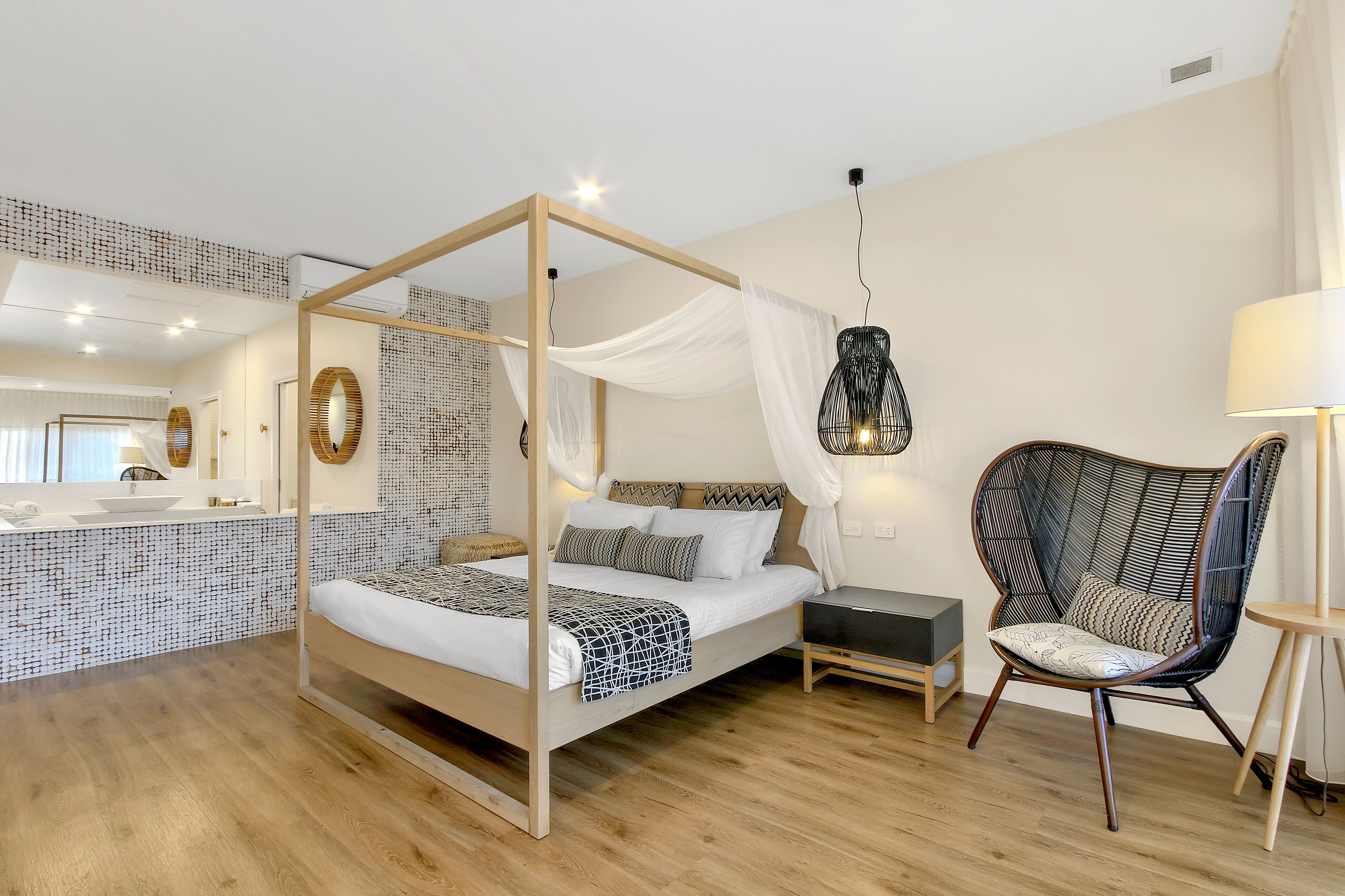A bedroom with a four-poster bed, a hanging chair, a bedside table, and a mirror.