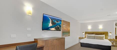 Ett hotellrum med en säng, ett skrivbord, en stol och konstverk på väggen.