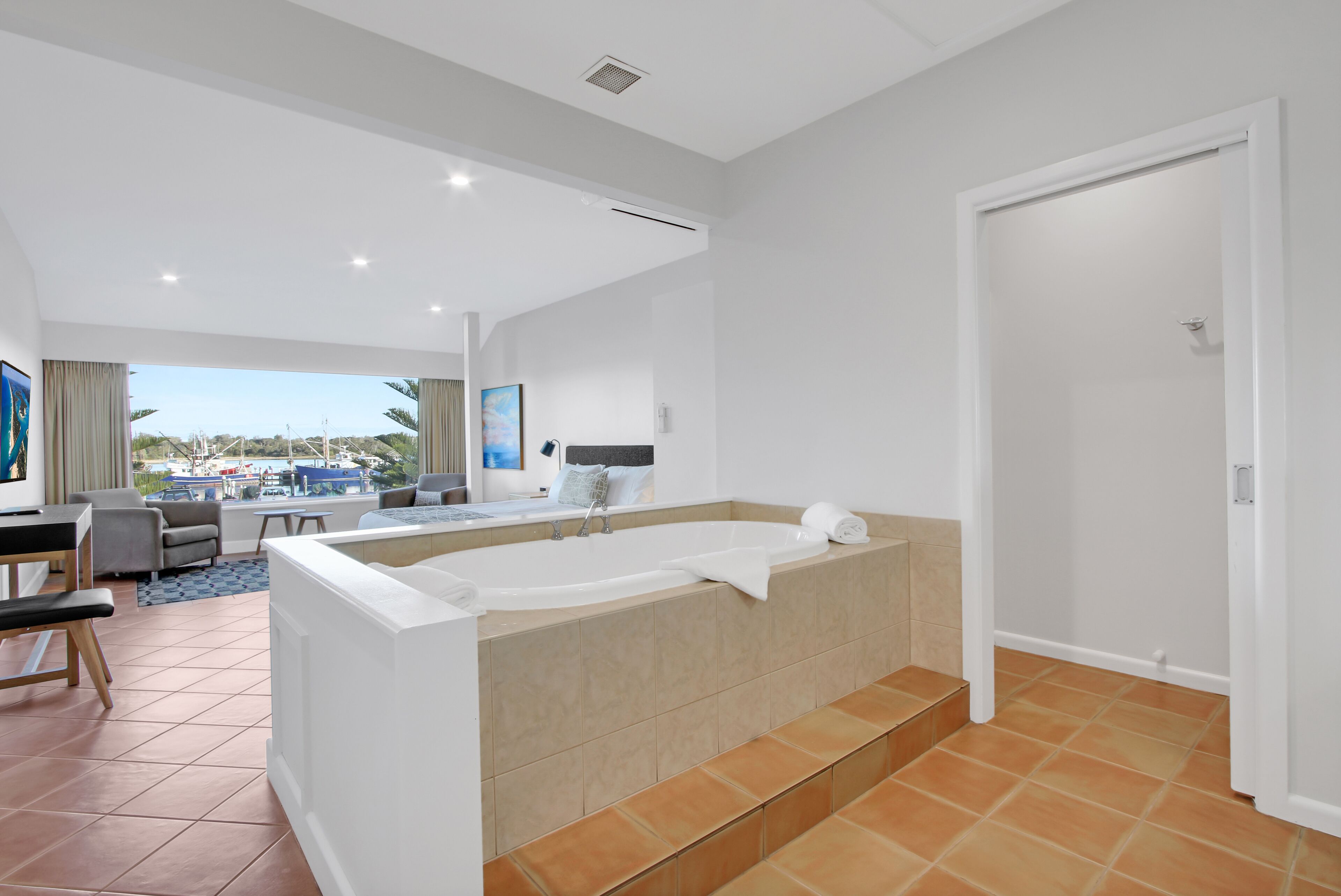 A modern bathroom with a large bathtub, a shower area, and a vanity with a mirror.