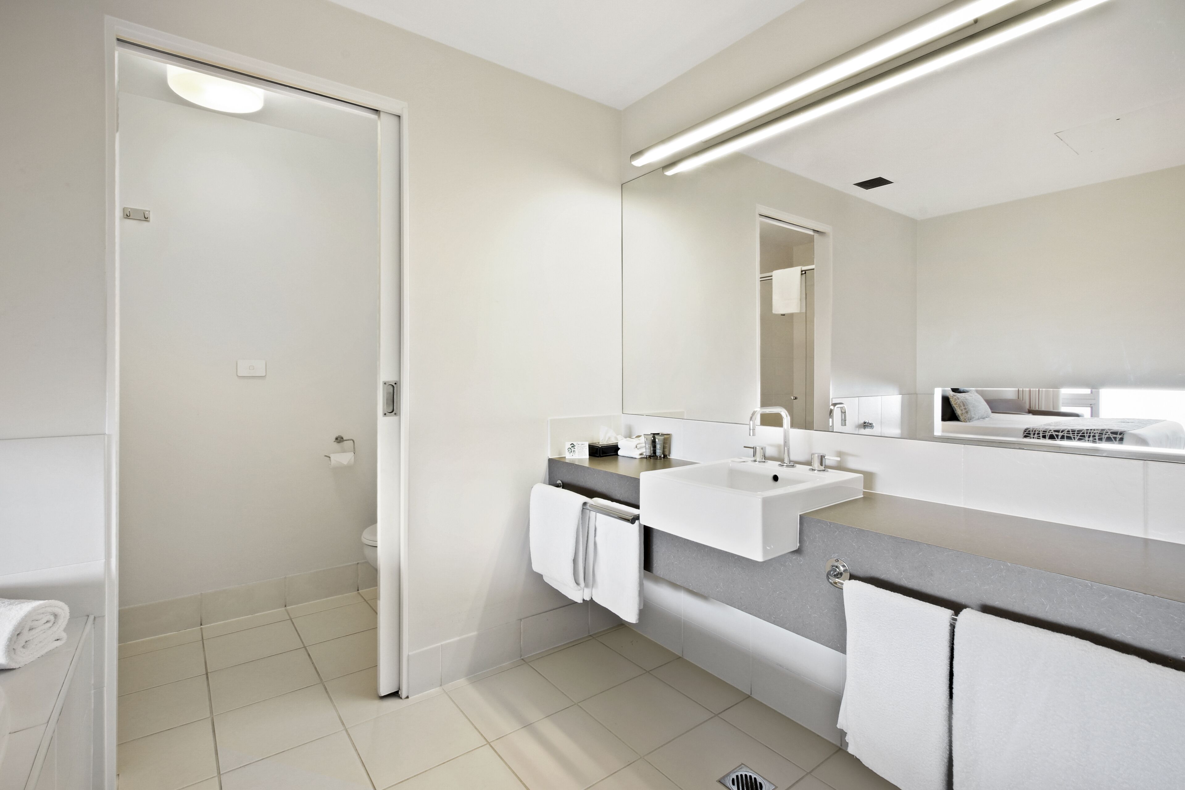 A modern bathroom with a white sink, a mirror, and a towel rack.