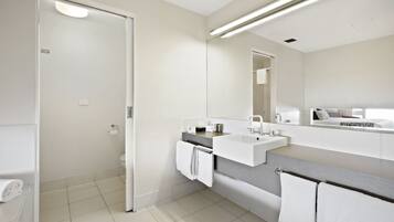 A modern bathroom with a white sink, a mirror, and a towel rack.