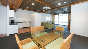Habitación de hotel moderna con zona de comedor, kitchenette y un amplio ventanal que proporciona luz natural.