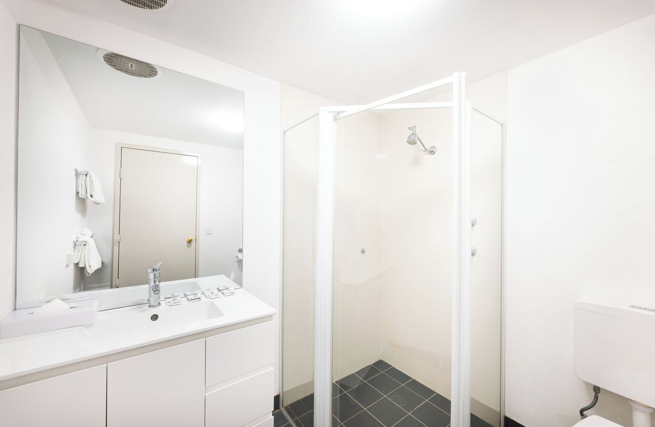 Un baño moderno con tocador blanco, cabina de ducha de vidrio y un inodoro.
