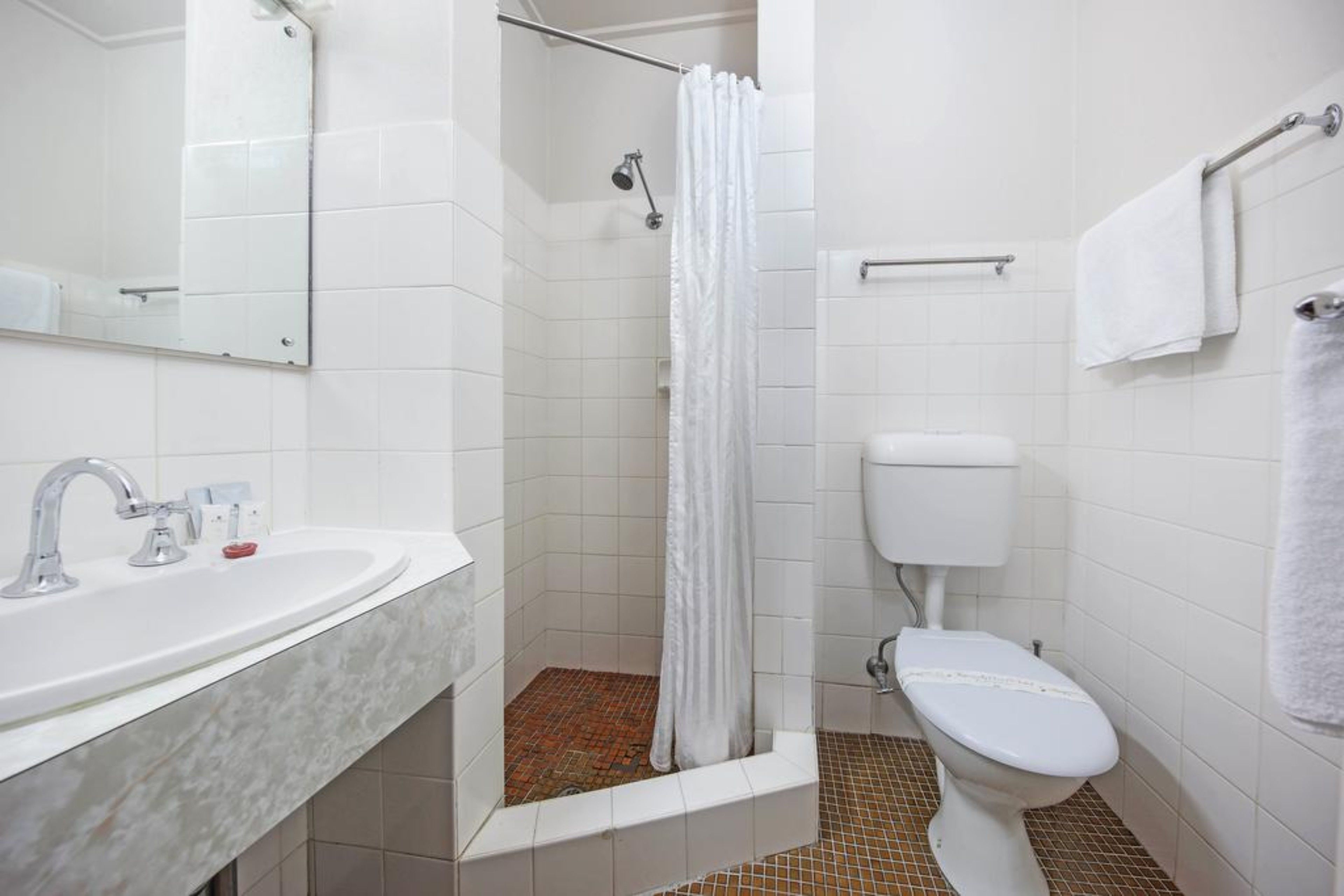 A bathroom with a white sink, a toilet, and a shower with a curtain.