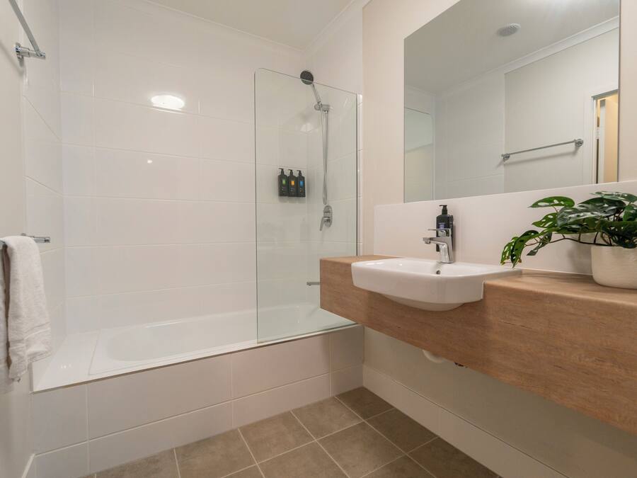 A modern bathroom with a glass-enclosed shower, a white sink, and a mirror above it.