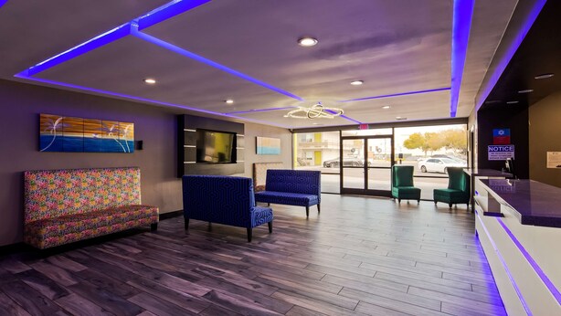 A reception area with a wooden floor, blue patterned chairs, a colorful sofa, and artwork on the walls. - SureStay Plus Hotel by Best Western Point Richmond (Richmond)