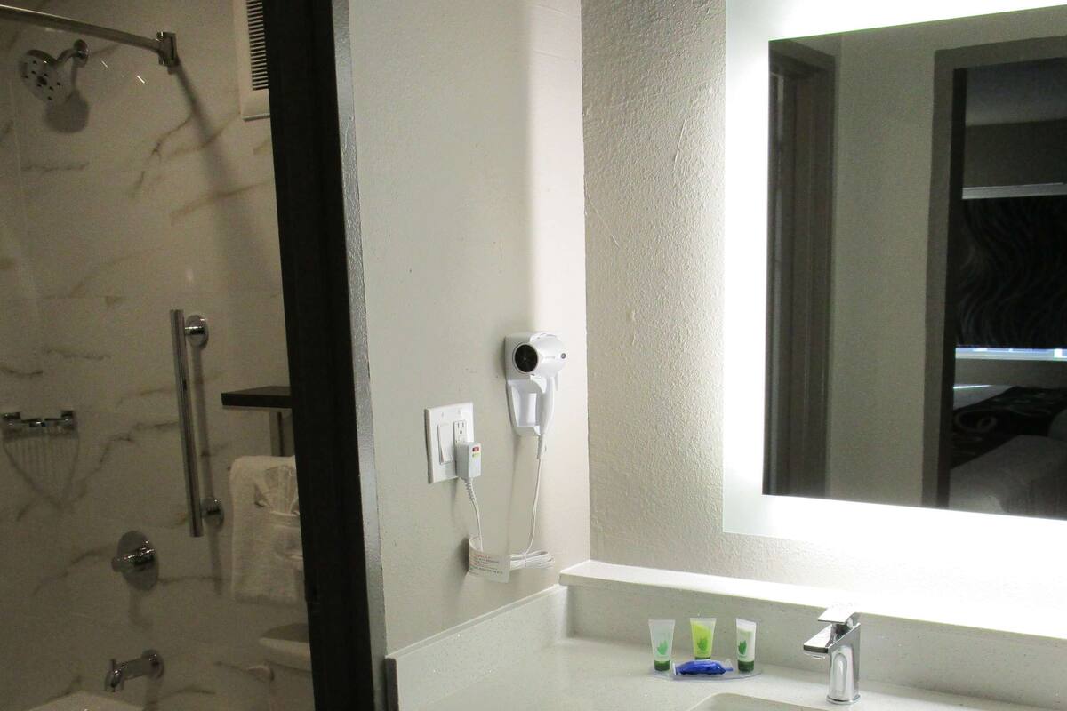 Ein modernes Badezimmer mit einer gläsernen Duschkabine, einer weißen Toilette und einem Waschbecken mit Spiegel darüber.