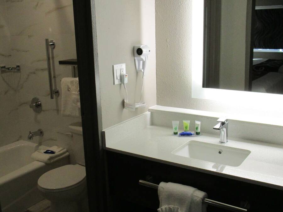 A modern bathroom with a glass-enclosed shower, a white toilet, and a sink with a mirror above it.