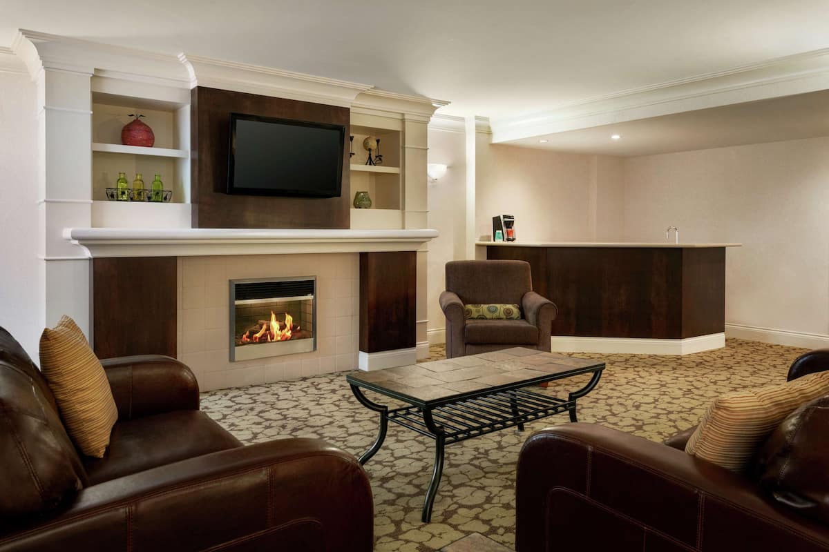 A living room with a fireplace, leather sofas, a coffee table, and a TV mounted on the wall.