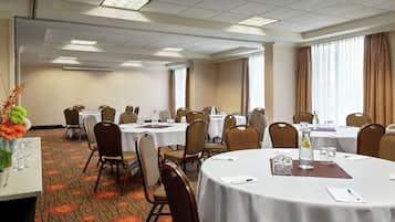Une salle de conférence avec des tables rondes, des chaises et un sol recouvert de moquette.