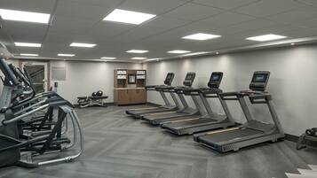 Un gimnasio con cintas de correr, elípticas y equipo de pesas.
