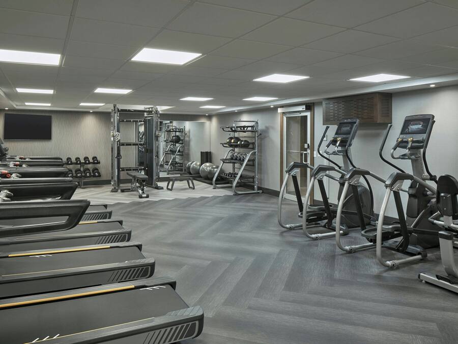 Un gimnasio con cintas de correr, elípticas y equipo de levantamiento de pesas.