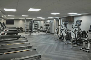 Un gimnasio con cintas de correr, elípticas y equipo de levantamiento de pesas.
