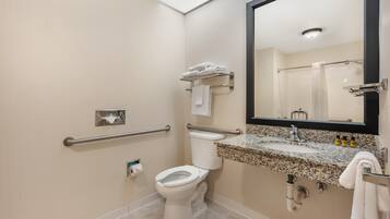 A modern bathroom with a toilet, sink, and handrails.