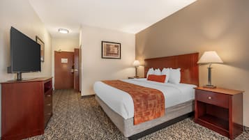 A hotel room with a bed, two bedside tables with lamps, a TV on a stand, a door, and a patterned carpet.