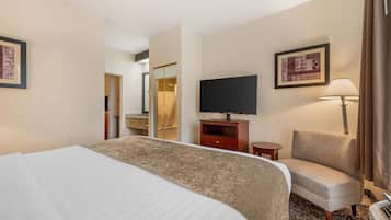 Una camera d'albergo con un letto grande, una televisione su un mobile in legno, una sedia, una scrivania e uno specchio.