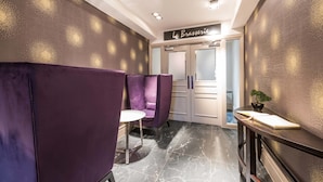 Ein modernes Interieur mit einer Rezeption, violetten Sitzgelegenheiten und einem Schild mit der Aufschrift 'La Brasserie'.