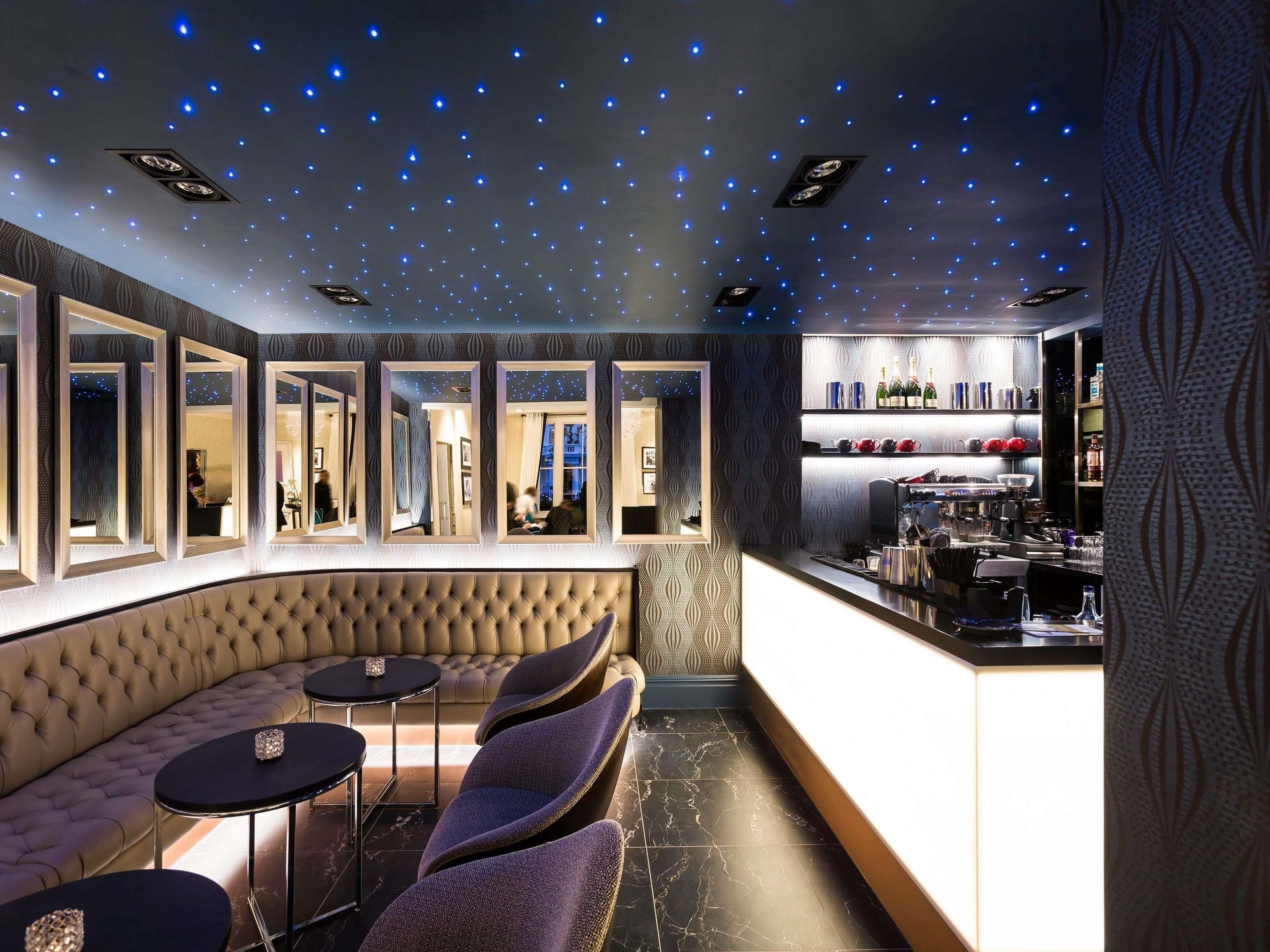 Eine Bar mit einer gebogenen Sitzgruppe, einer Bar und einer Spiegelwand, die das Interieur widergibt.