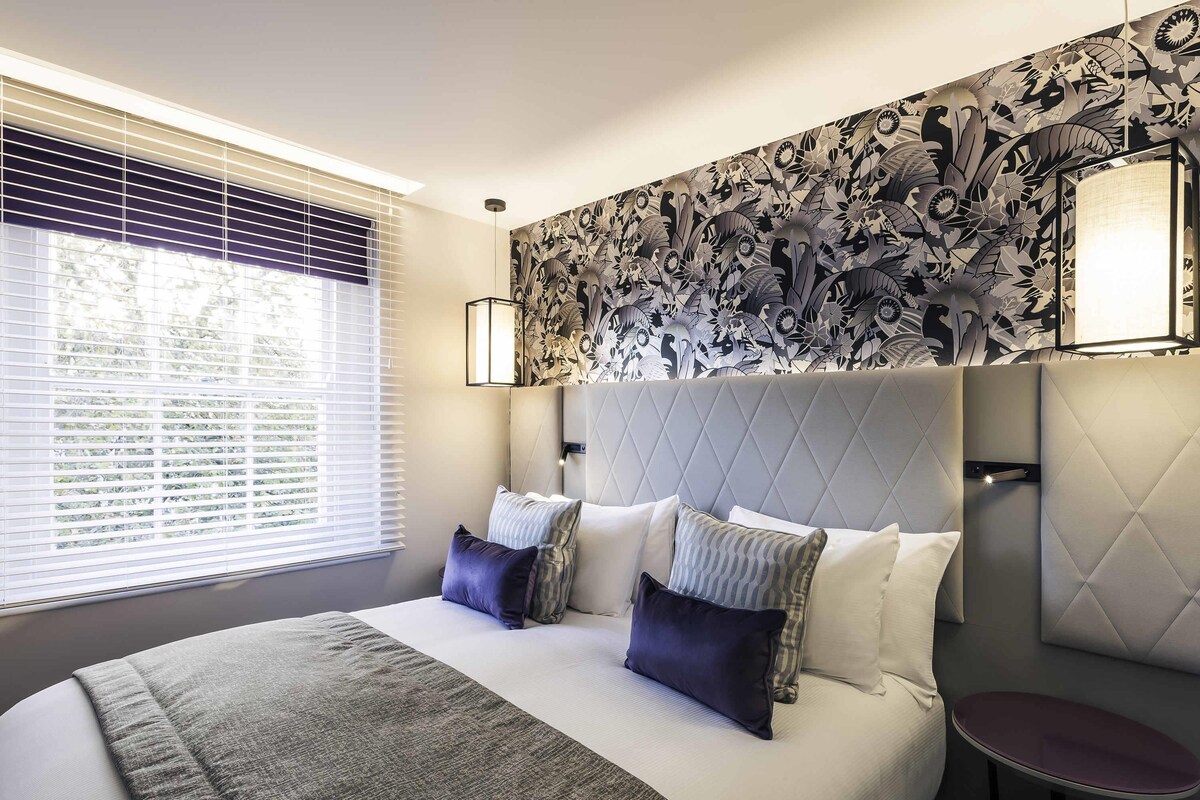 Een moderne hotelkamer met een groot bed, een nachtkastje en een decoratieve wand.