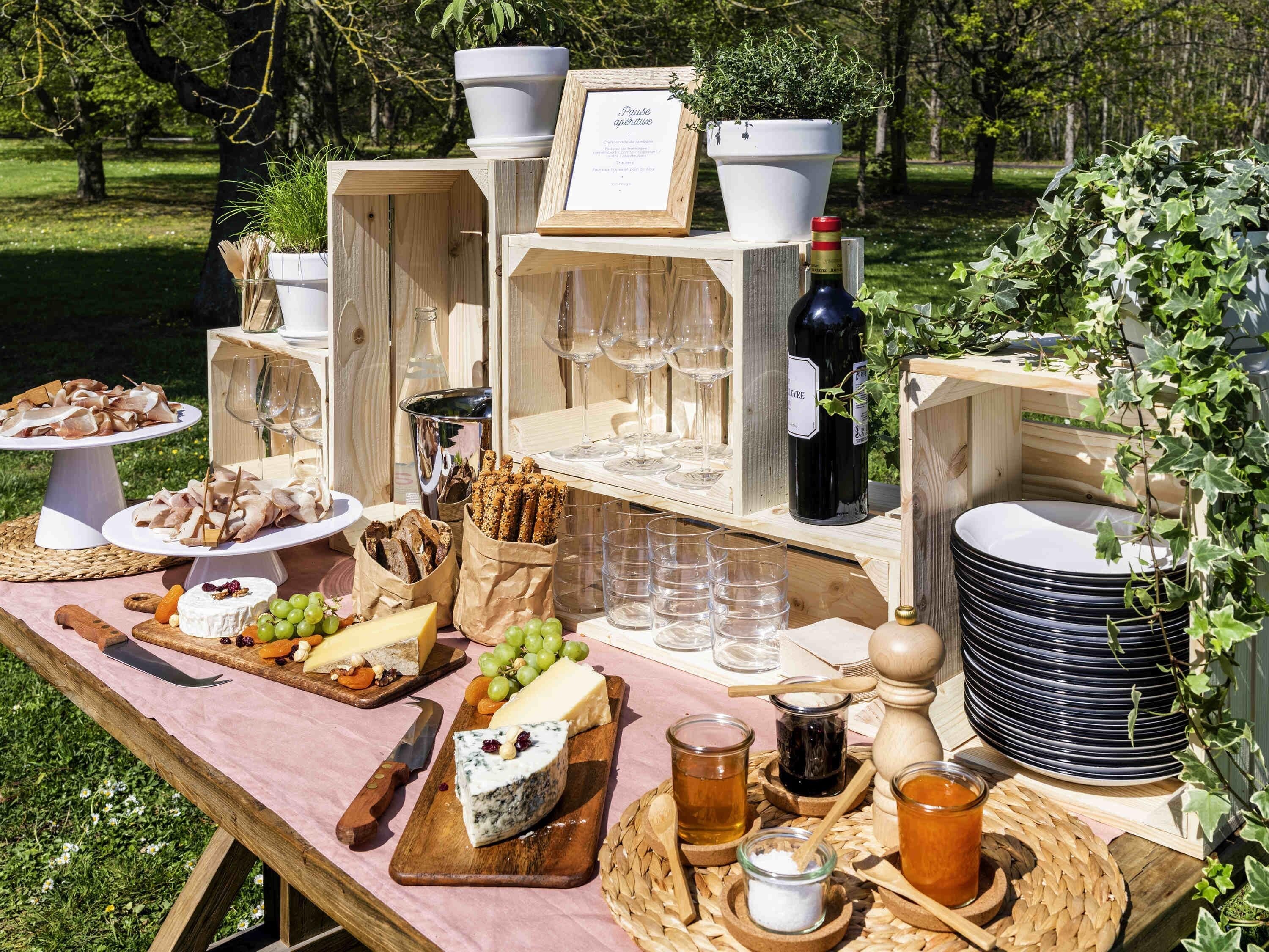 Ein Picknick im Freien mit verschiedenen Käsesorten, Brot und einer Weinflasche.