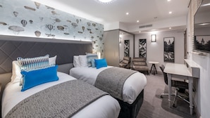 Ein modernes Hotelzimmer mit zwei Betten, einem Schreibtisch und einer Sitzecke.