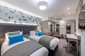 Een moderne hotelkamer met twee bedden, een bureau en een zithoek.